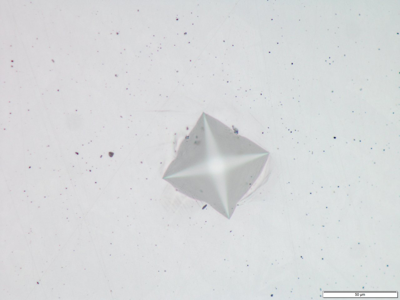 Micrografía de una huella de dureza Vickers en acero 1.4301 con un aumento de 50× y una barra de escala de 50 µm.
